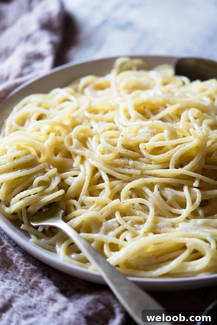 A side shot of a cacio e pepe recipe on a plate with a fork