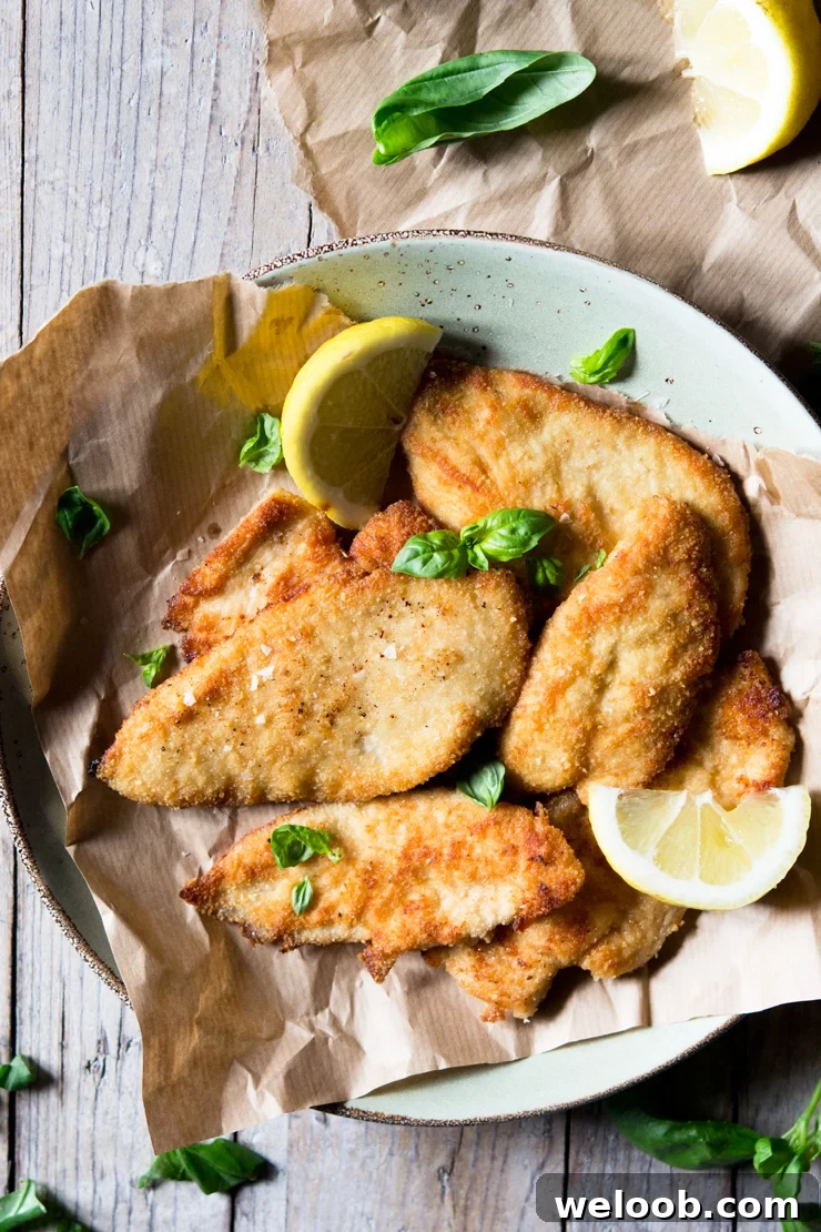 An overhead shot of breaded chicken cutlets on a plate garnished with basil