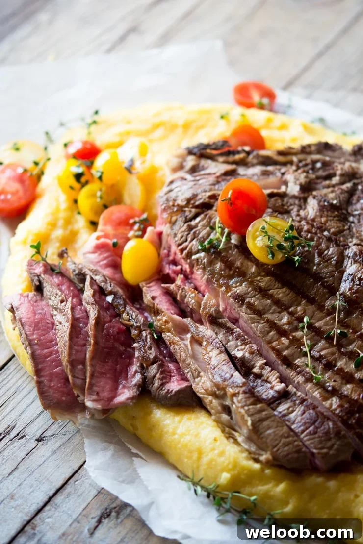 A side view of a florentine steak cut into slices (rare) topped with cherry tomatoes