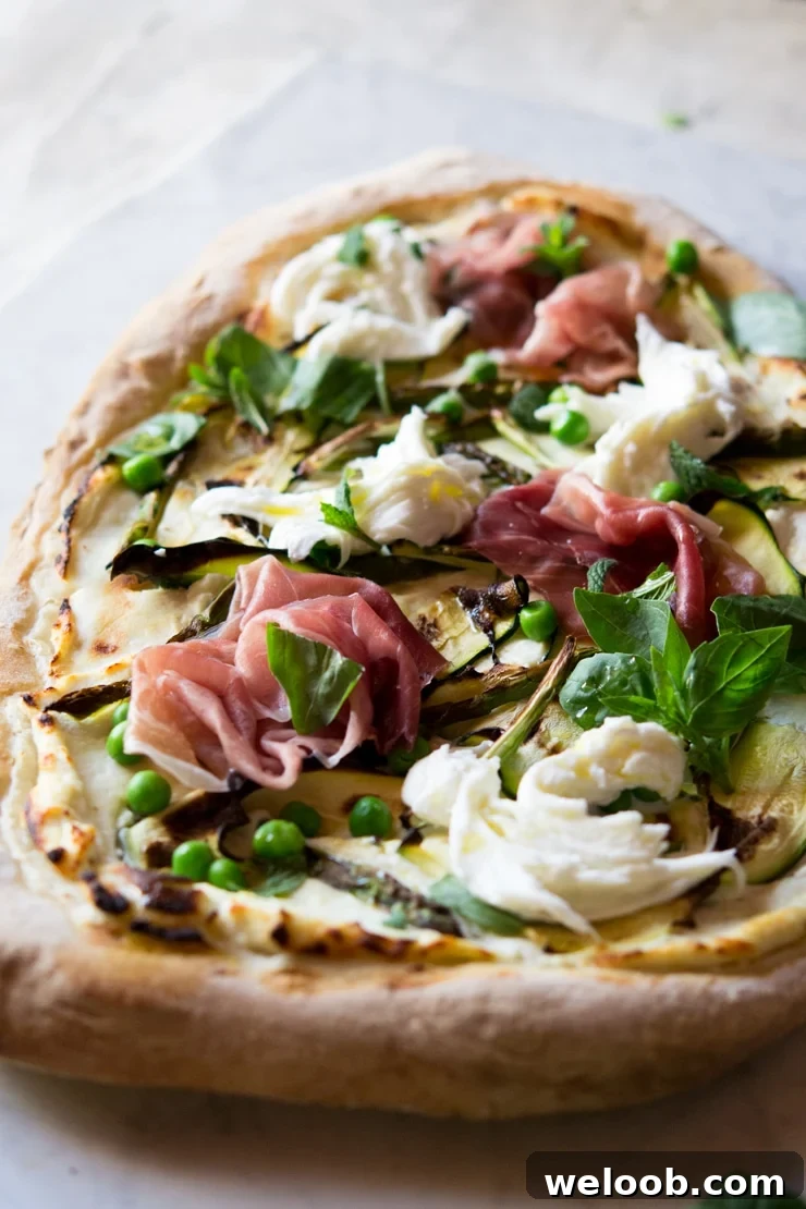 A close up of pizza with zucchini, asparagus and prosciutto