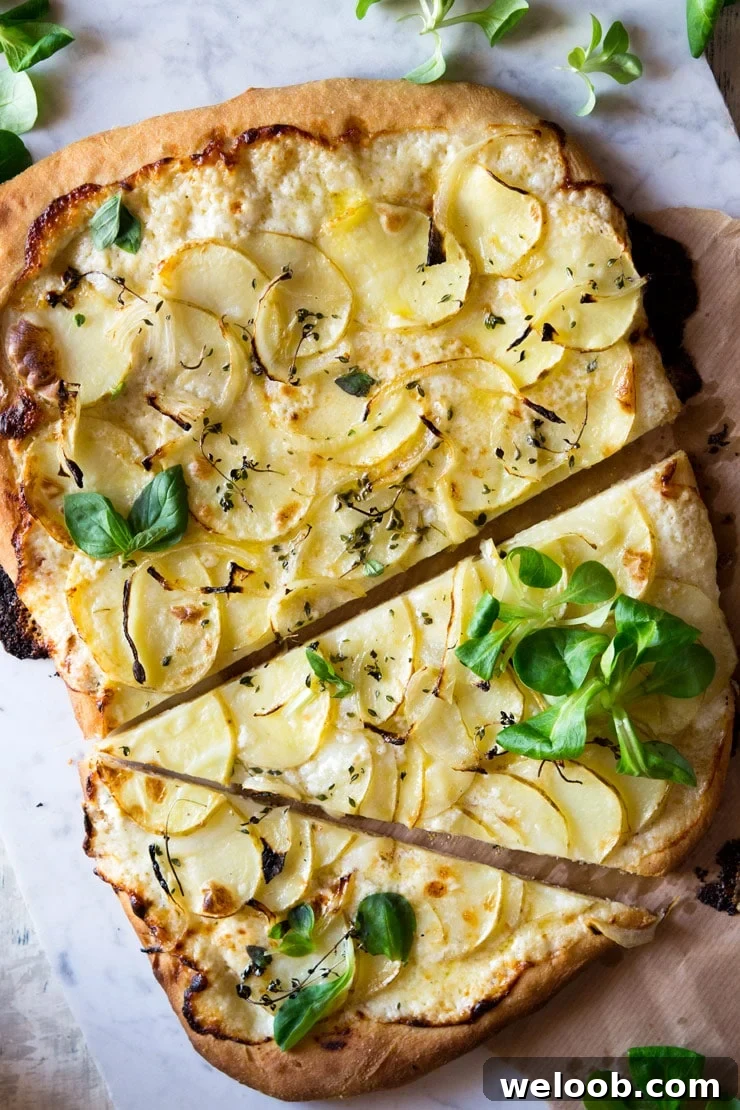 An overhead shot of a cheesy potato pizza with a large slice cut