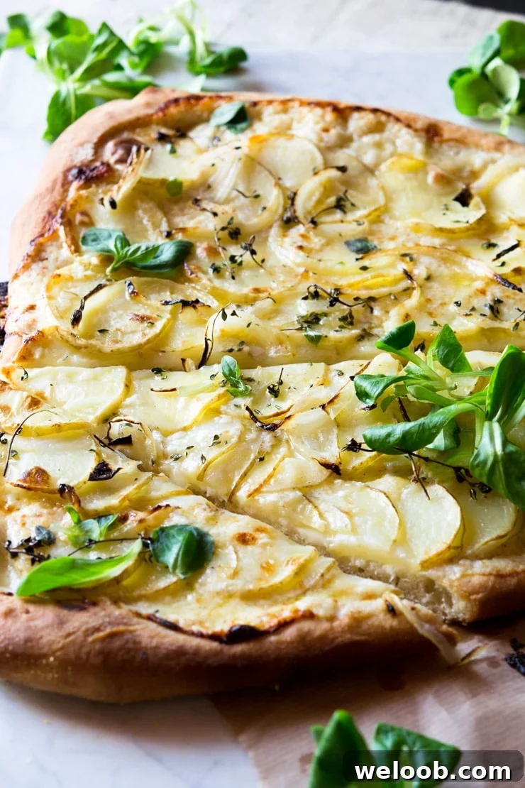 A side shot close up of a potato pizza on a marble work surface