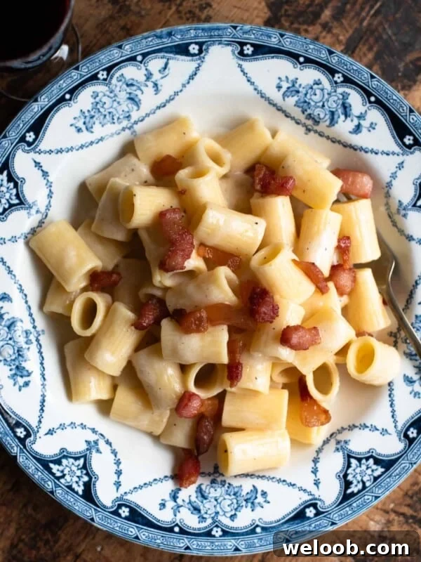 Pasta alla Gricia in a white and blue vintage style bowl sitting on a wooden surface.
