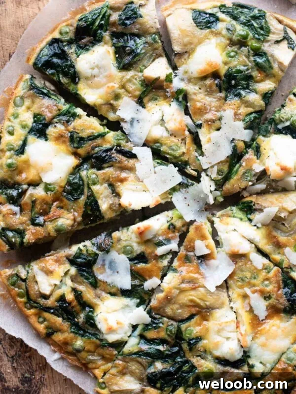 An overhead shot of a spinach and artichoke frittata cut into slices sitting on a wooden cutting board.