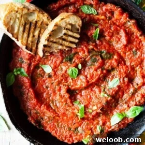 A close up overhead shot of tomato sauce in a skillet with two slices of char-grilled bread at the side.
