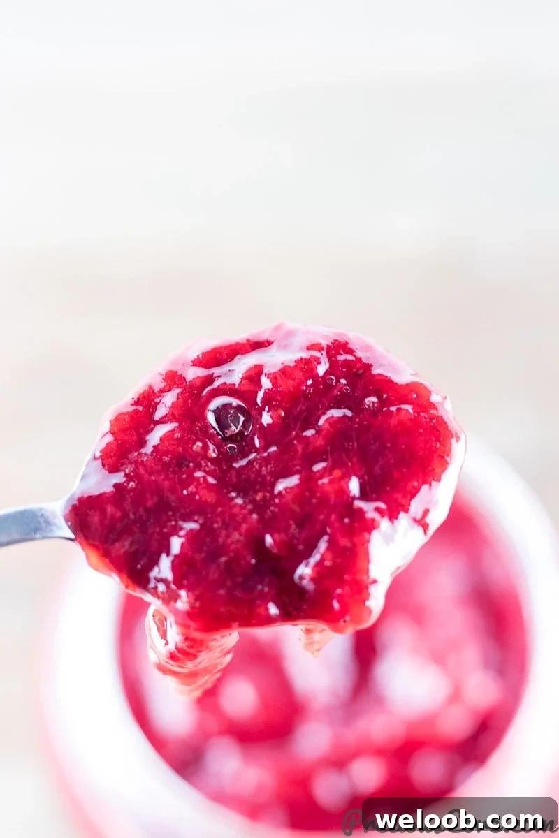 Spoon scooping strawberry jam.