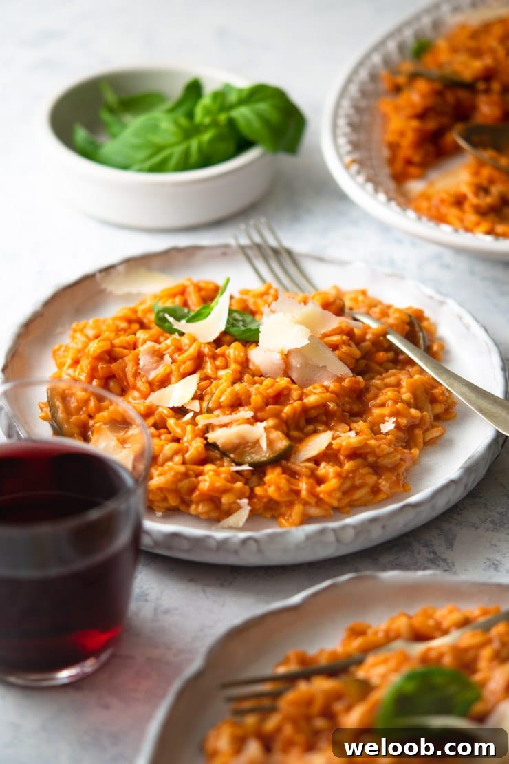 A plate of tomato risotto with a fork and a glass of red wine at the side