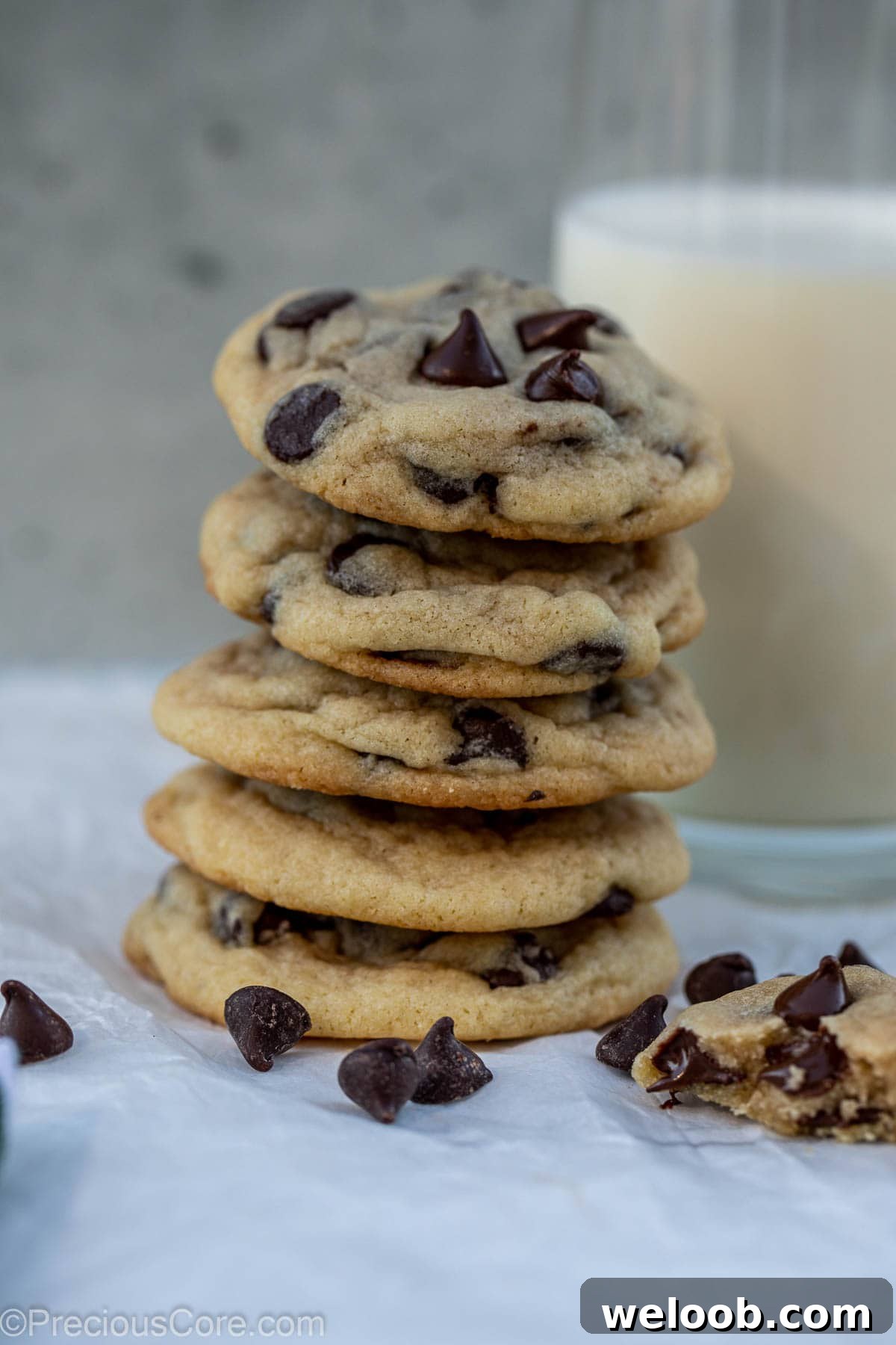 Tall stack of cookies with a glass of milk behind.