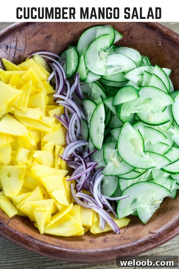 Bowl of unmixed salad with text "Cucumber Mango Salad."