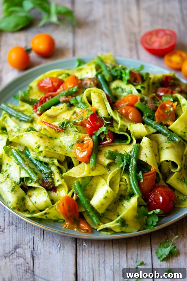 A side shot of pasta with green beans and tomatoes
