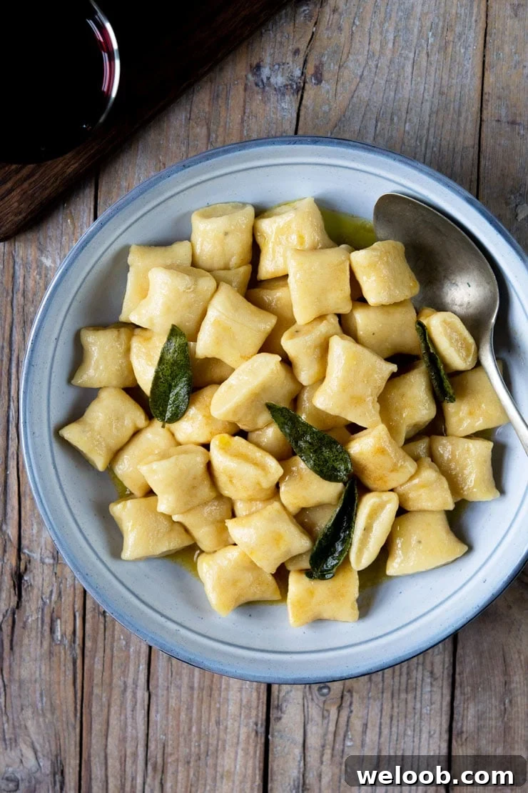An overhead shot of gnocchi in a brown butter sage sauce in a large blue bowl