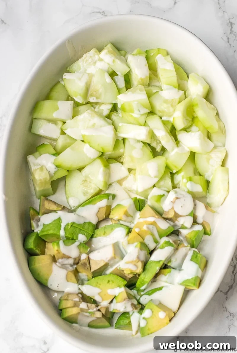 Cucumber Avocado Salad in a bowl with Mayonnaise Dressing drizzled on top