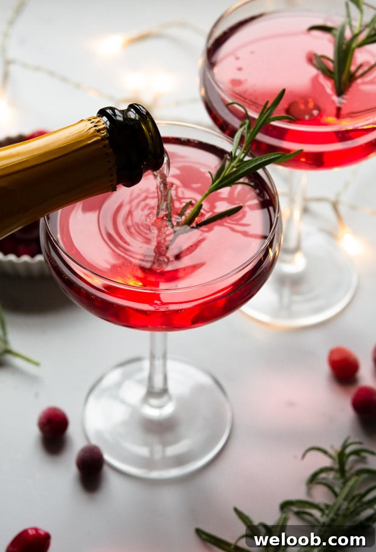 Someone pouring a Christmas cocktail topped with rosemary