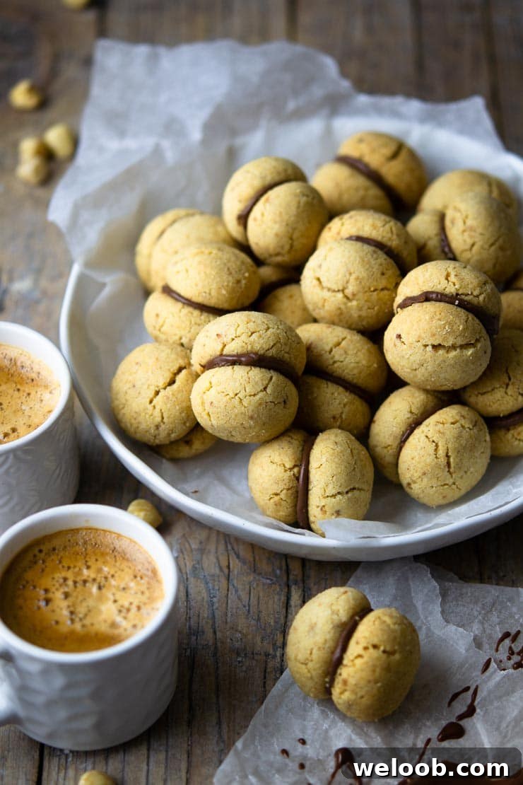 A close up of lady's kisses cookies in a bowl with two cups of coffee at the side