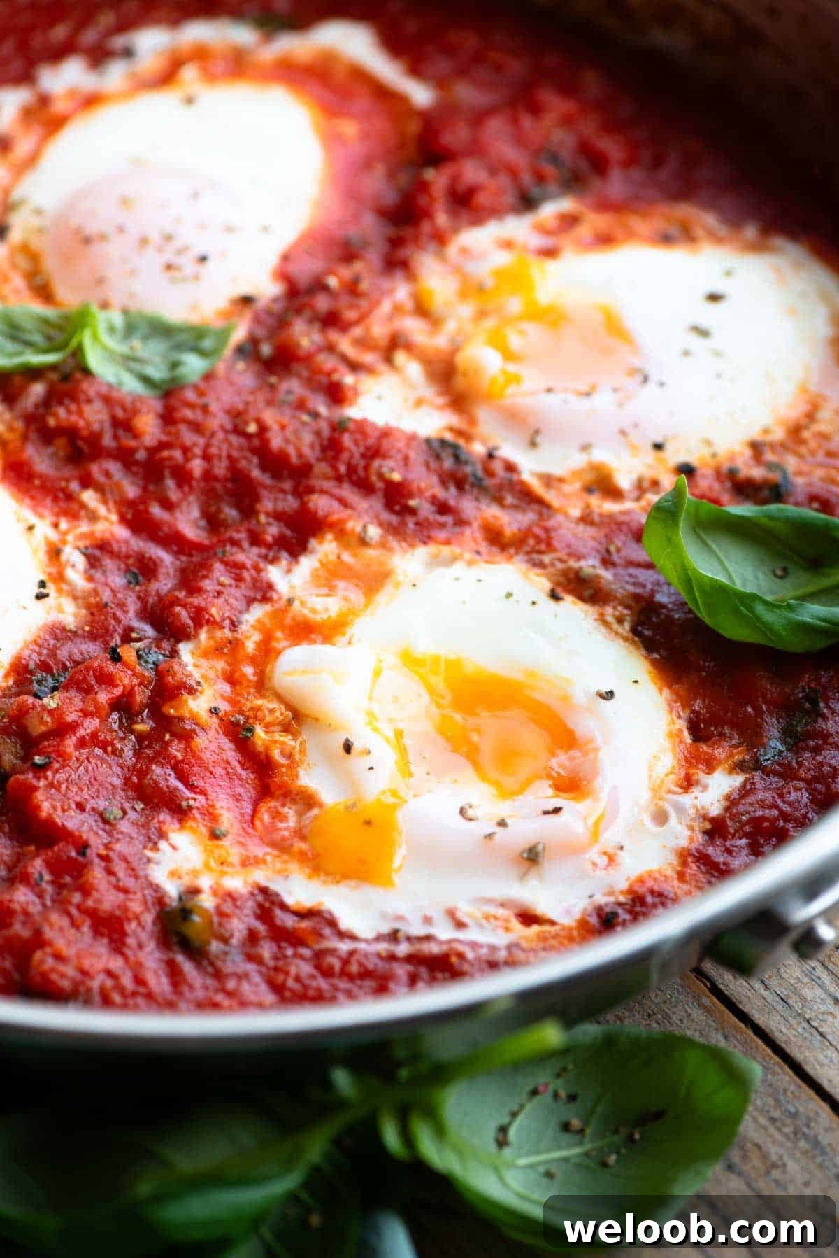 A close up of eggs in purgatory with a runny yolk in a pan.