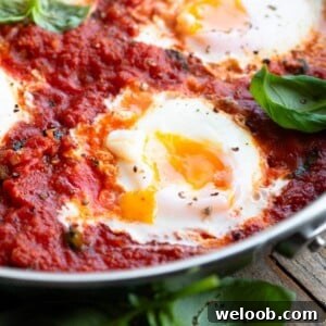 A close up of a perfectly cooked poached egg in tomato sauce with a runny yolk.