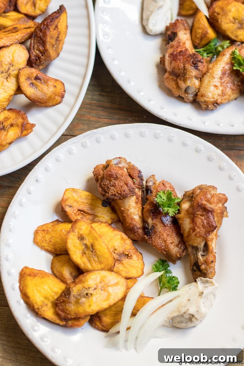 Sweet fried plantains on a white plate with oven grilled chicken wings.