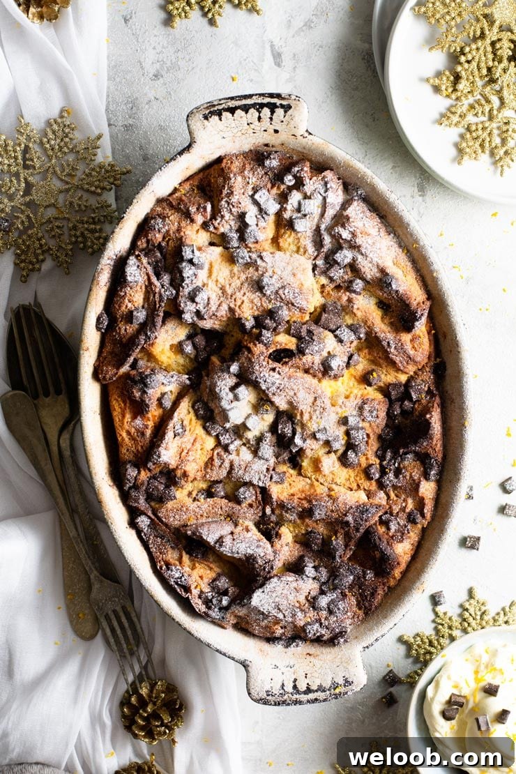 An overhead shot of panettone bread pudding in an oval baking dish with fresh cream at the side