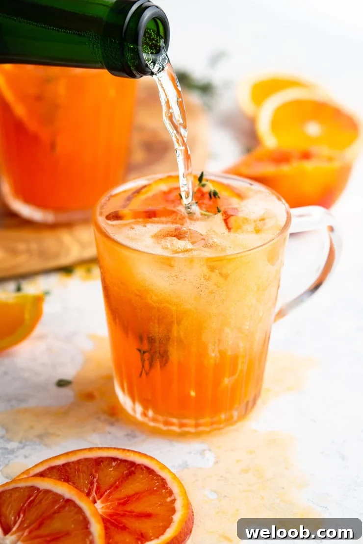 Prosecco getting poured into a blood orange cocktail
