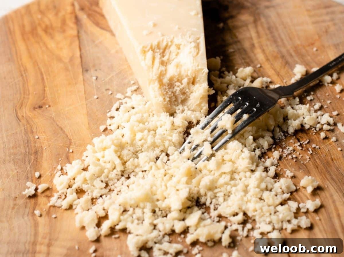 A close up of Parmigiano Reggiano being crumbled with a fork.