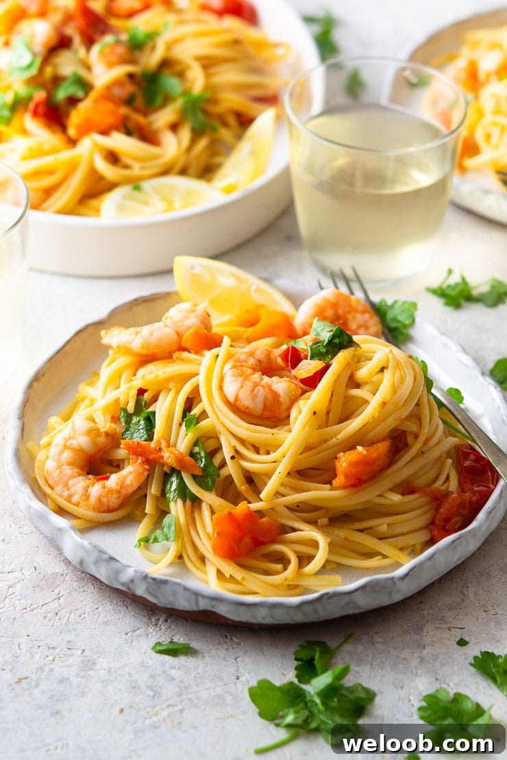 A close up of shrimp linguine on a plate with parsley and lemon