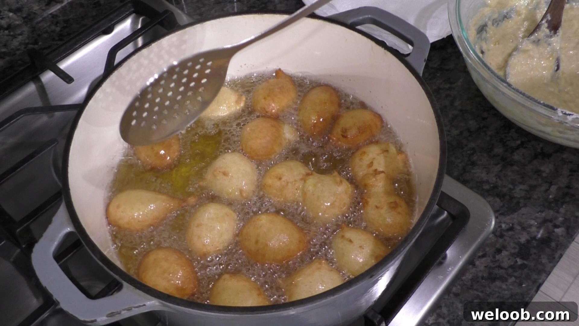 Fritters deep-frying in enameled cast iron pot.