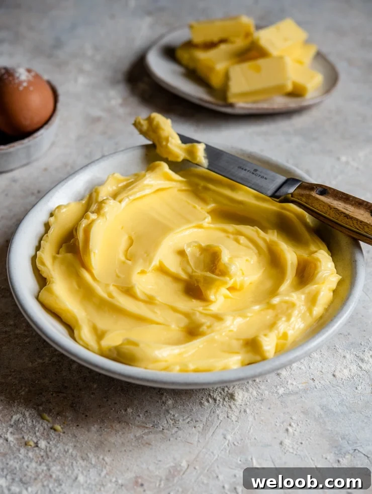A side shot of softened butter in a bowl with a knife