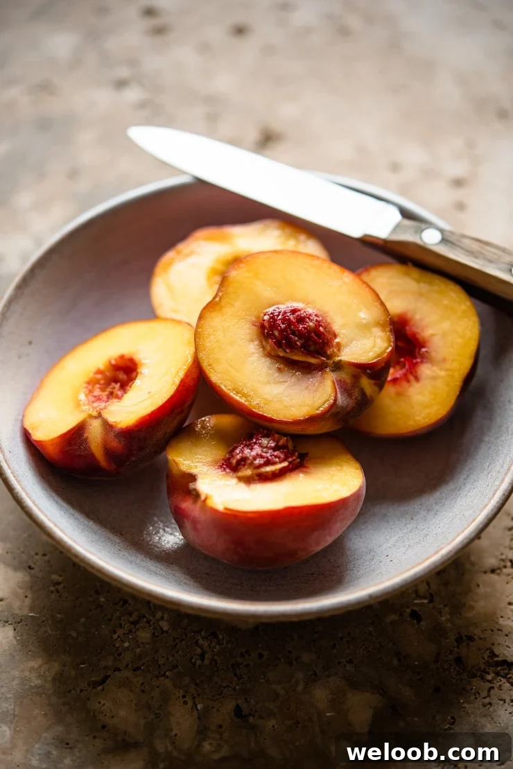 Fresh ripe peaches in a bowl with a knife at the side