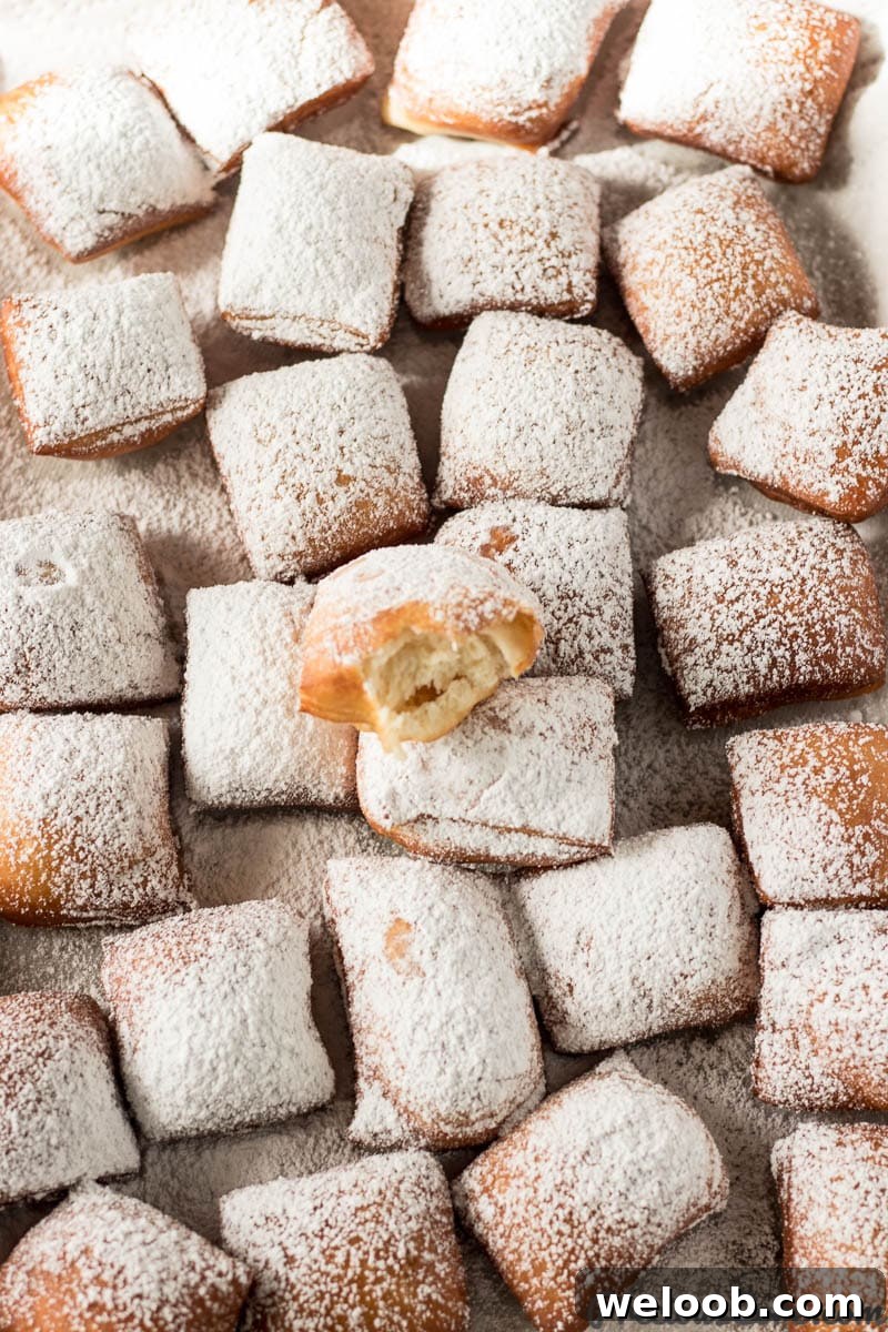 Tray of beignets, one of which is missing a bite.
