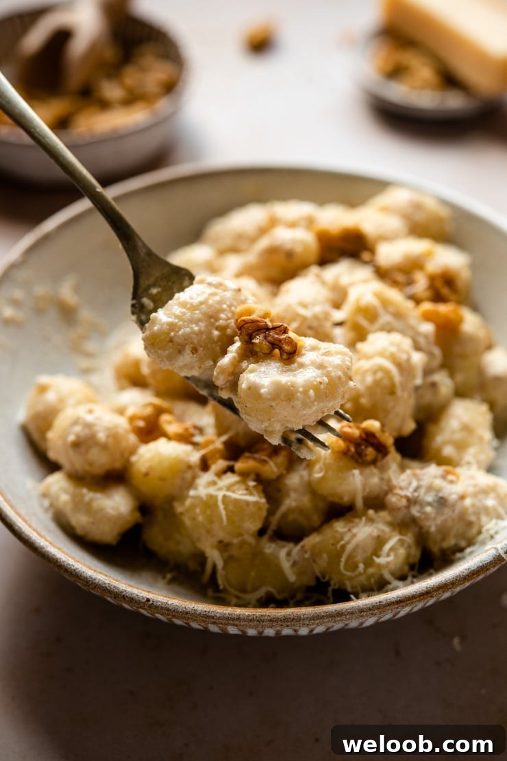 A close up of walnut sauce tossed with gnocchi on a fork