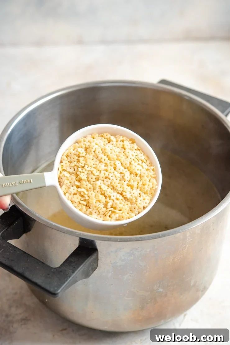 A photo of adding pastina pasta to chicken soup