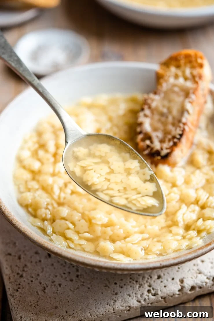 A close up of a spoonful of pastina soup