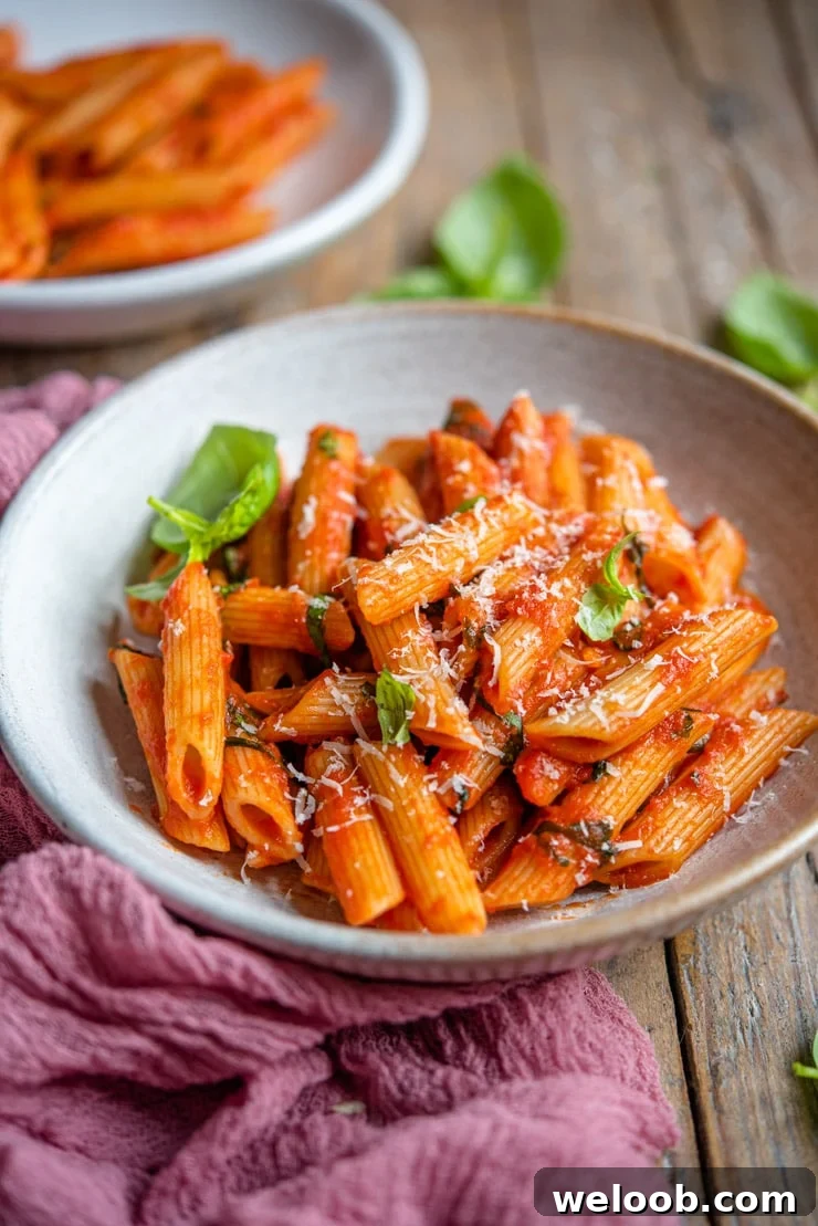 A side shot of penne pomodoro in a rustic bowl