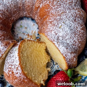 Lemon pound cake on a round platter with a piece of cake cut out.