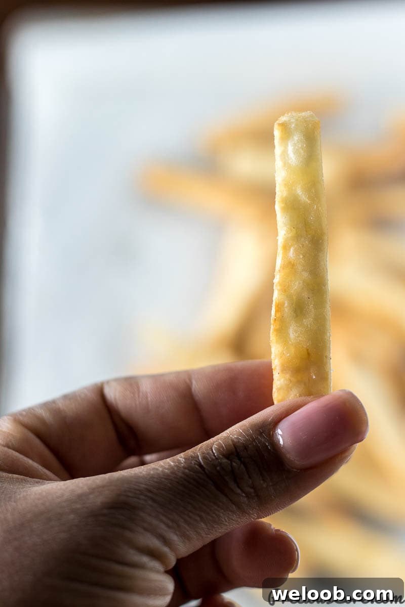 Hand holding a crispy yuca fry