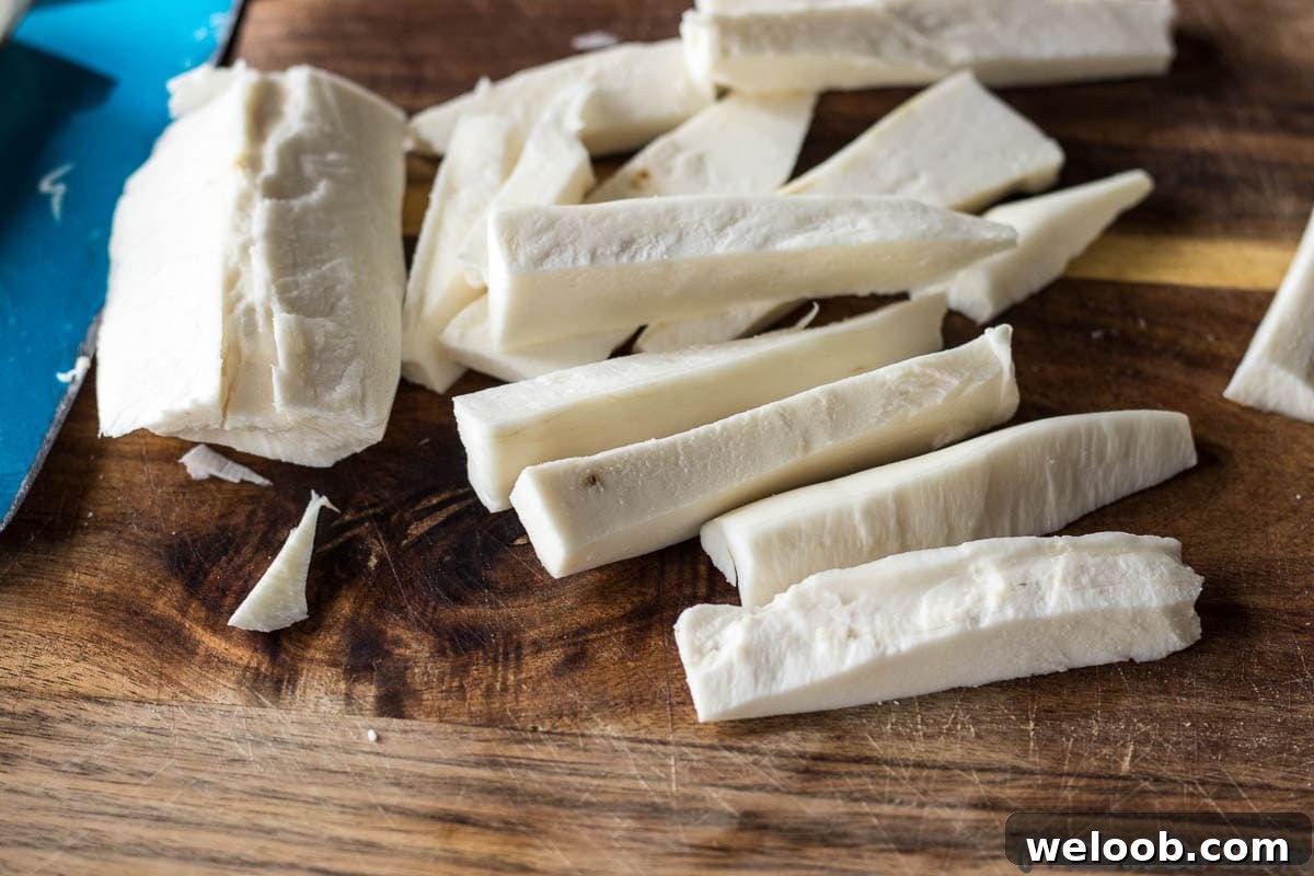 Yuca cut into fries on a chopping board.