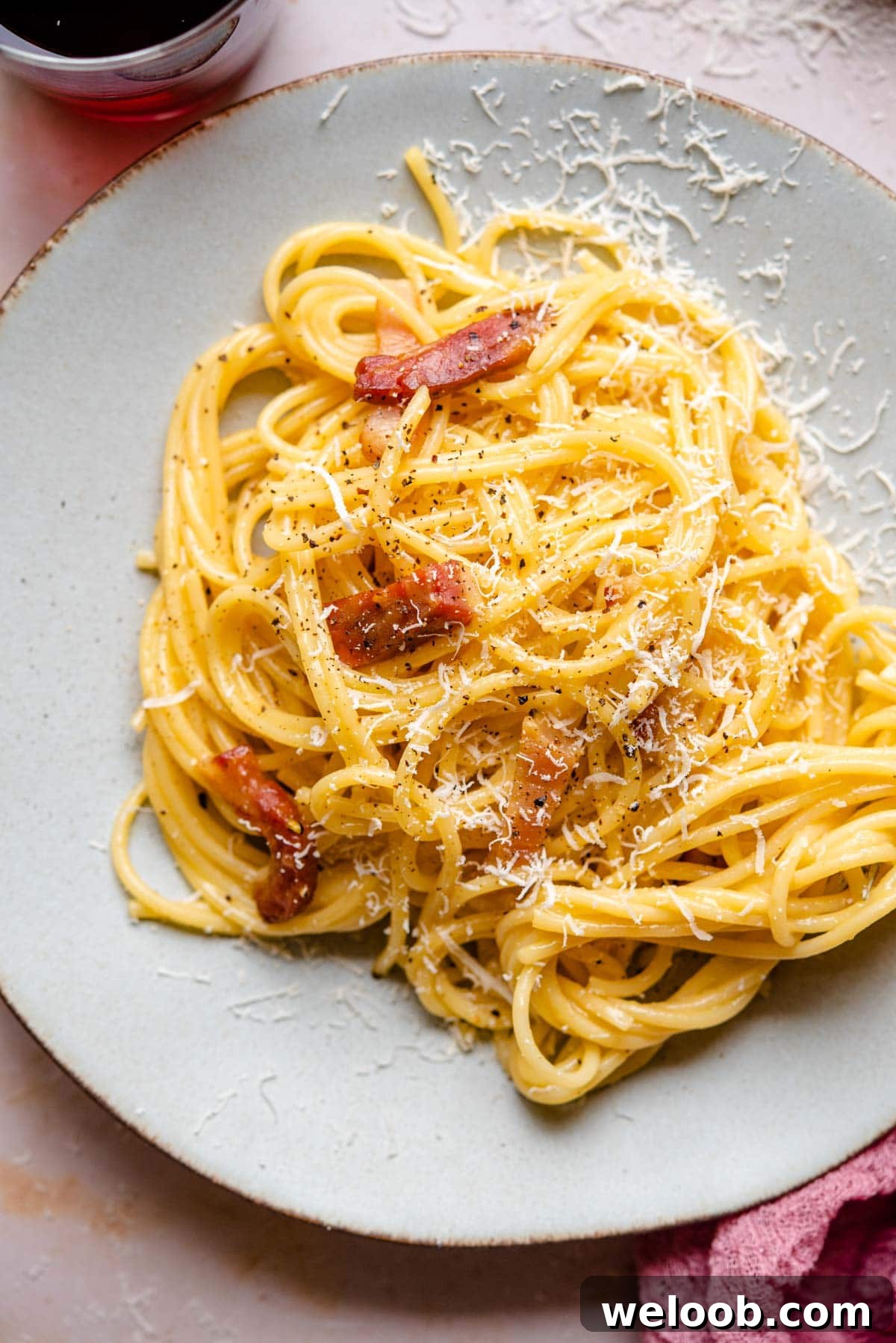A close up of spaghetti on a plate with pieces of guanciale