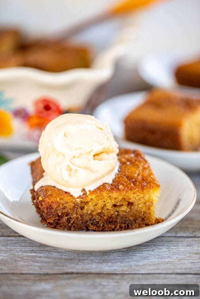 A slice of South African Malva Pudding Recipe topped with a scoop of ice cream.