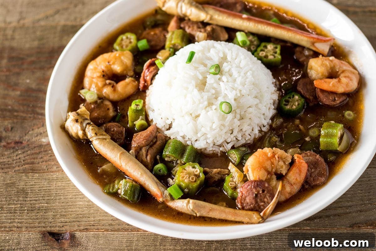 Seafood gumbo with shrimp and crab legs in a bowl with rice.