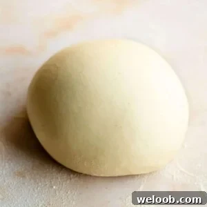 A close up of semolina pasta dough in a ball on a marble surface