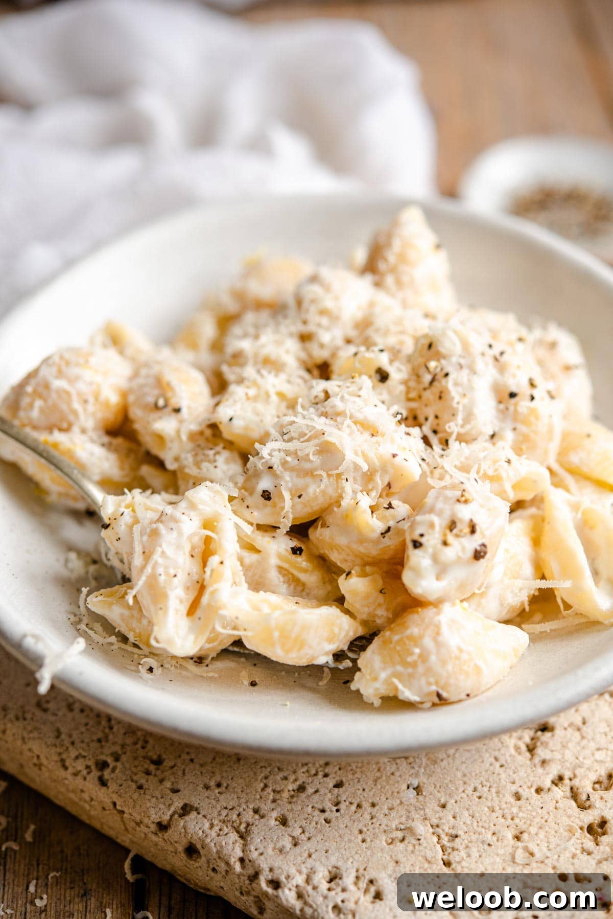 A side shot of pasta shells with a ricotta sauce in a ceramic bowl