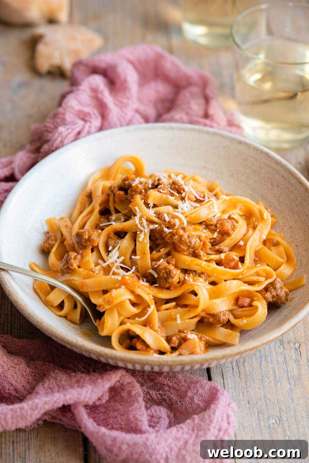 A side shot of bolognese sauce and tagliatelle in a rustic bowl