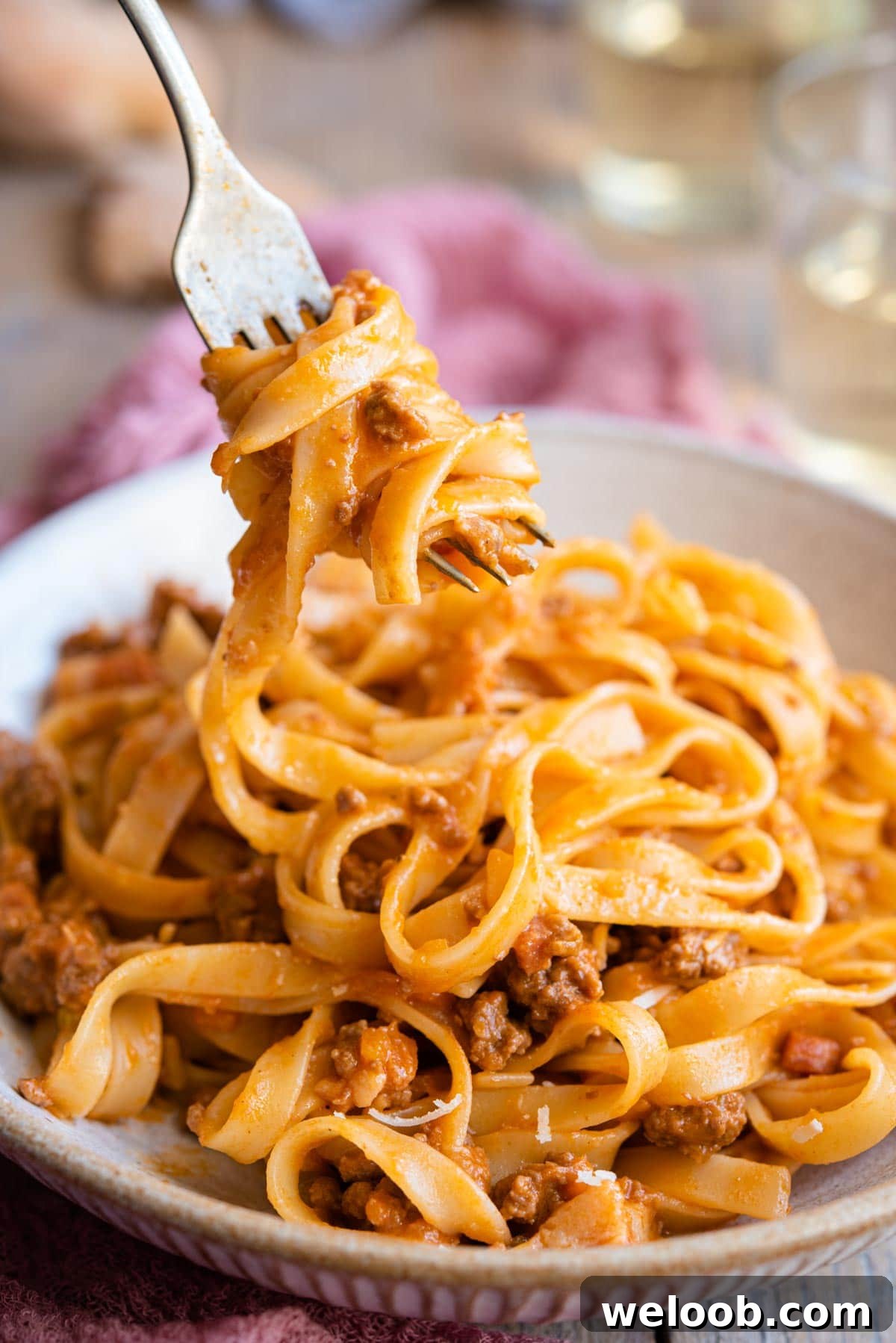 A close up of tagliatelle and bolognese sauce on a fork