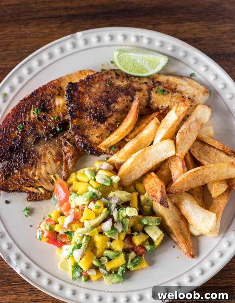 Grilled fish and a lime wedge with mango avocado salsa.