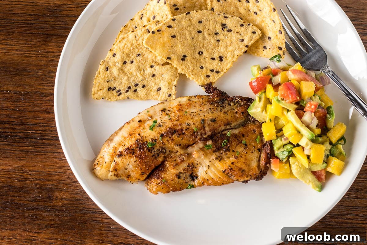 Pan Seared Tilapia on a plate with Mango Avocado Salsa and tortilla chips