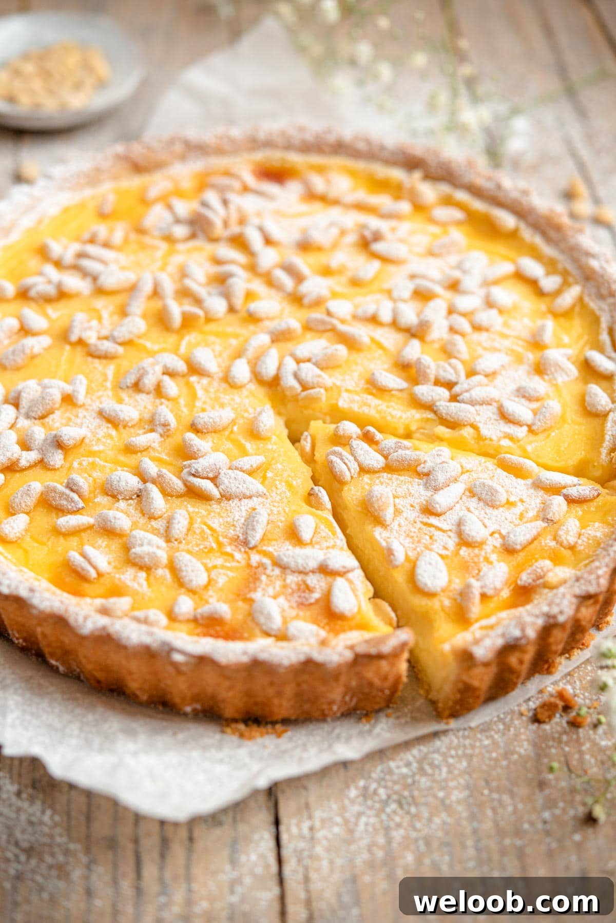 A side shot of an Italian custard tart with a slice cut out