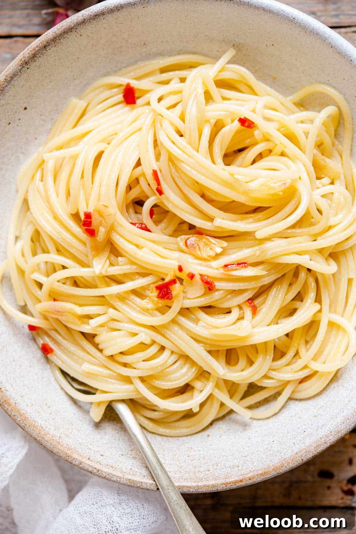 An overhead close up shot of spaghetti with garlic and oil in a bowl