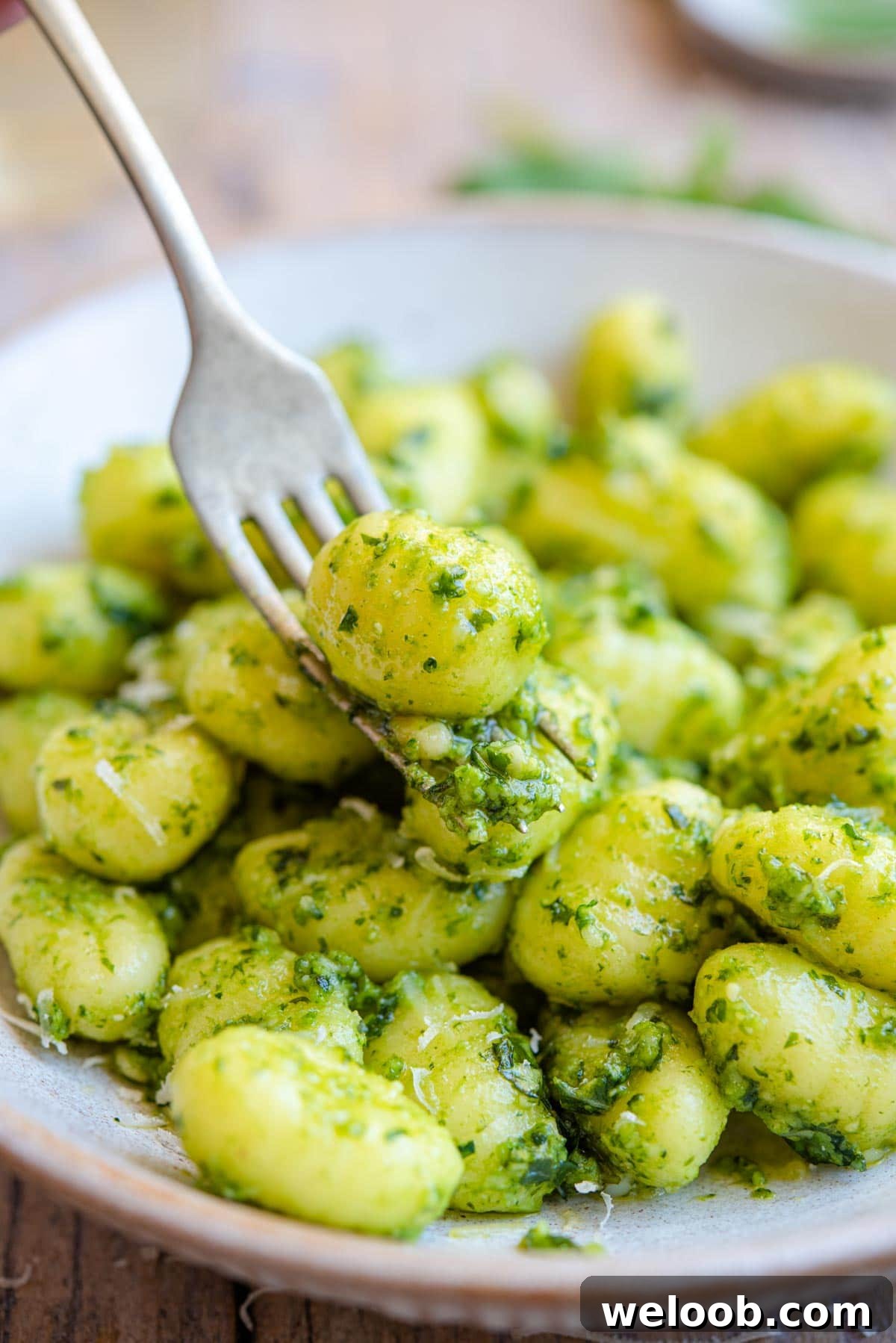 A close up of gnocchi and pesto sauce on a fork