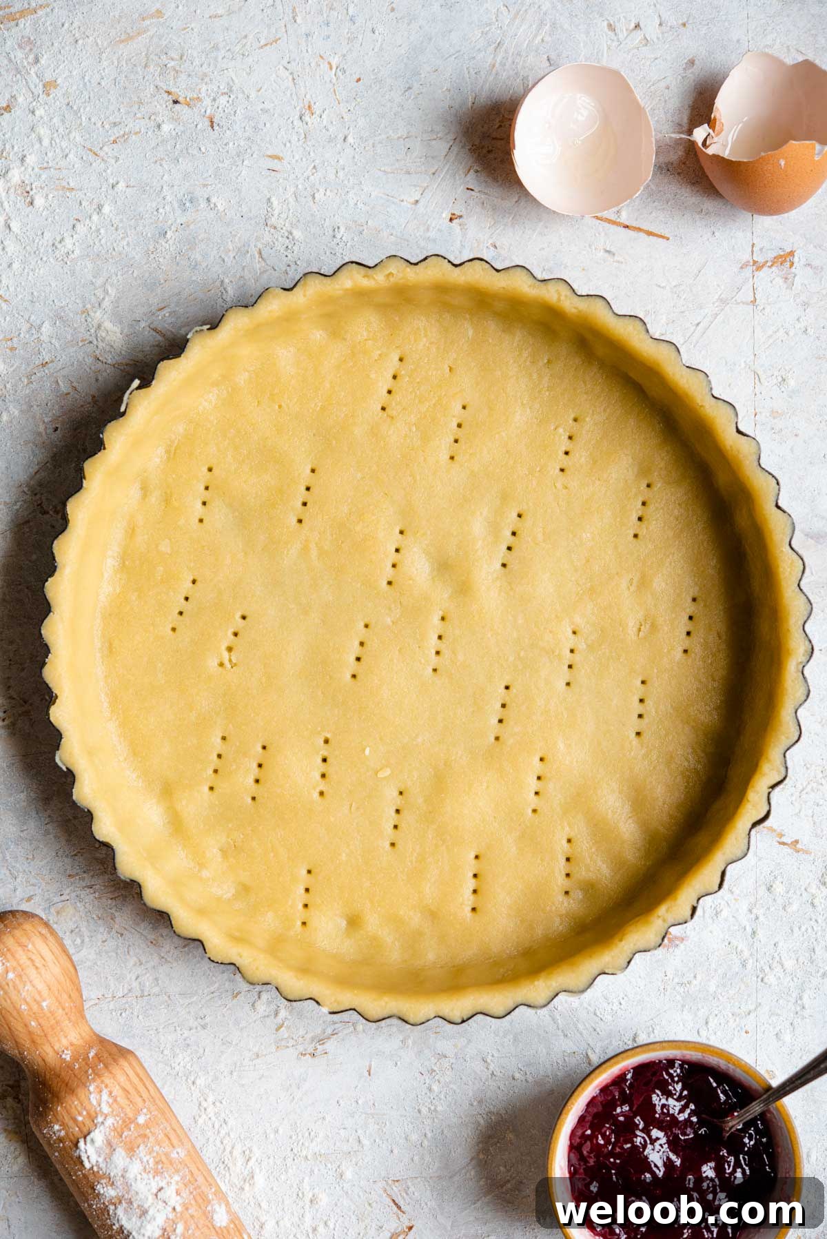 An overhead shot of raw sweet shortcrust pastry in a pie case