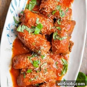 An overhead shot of beef braciole on a platter with tomato sauce
